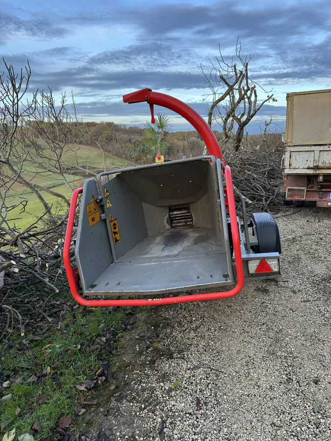 Broyeur de branches installé devant un tas de branches à traiter
