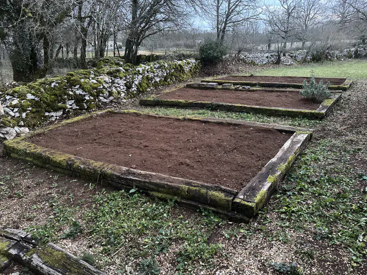 Plusieurs parcelles de potager nettoyées et préparées dans un jardin